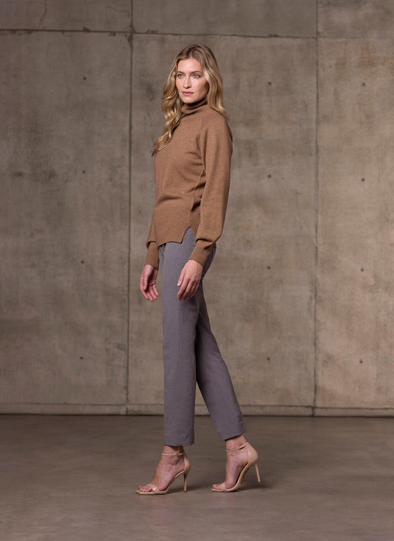 side image of Women's Cinzia Turtle Neck Cashmere Sweater in Camel with light grey pants and neutral heels