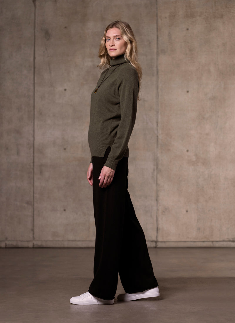 side image of Women's Cinzia Turtle Neck Cashmere Sweater in Olive featuring our cashmere wide leg pant in black 