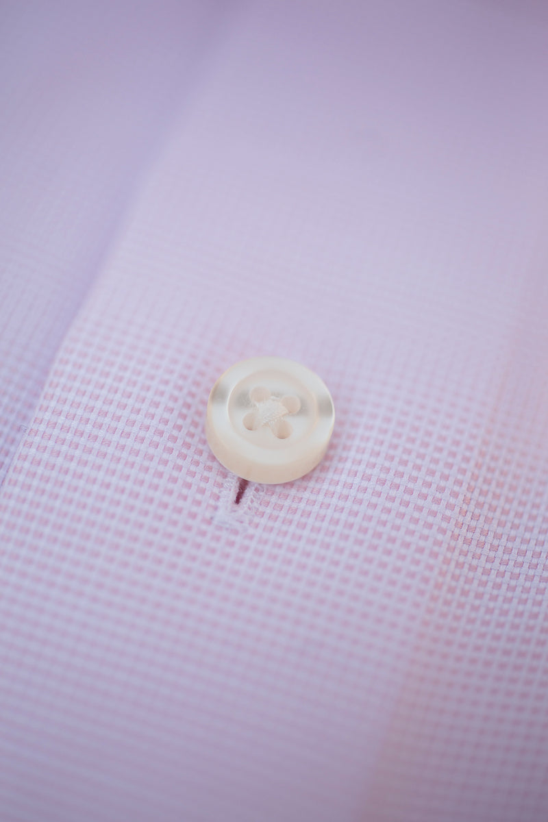 solid pink textured fabric with white button and thread