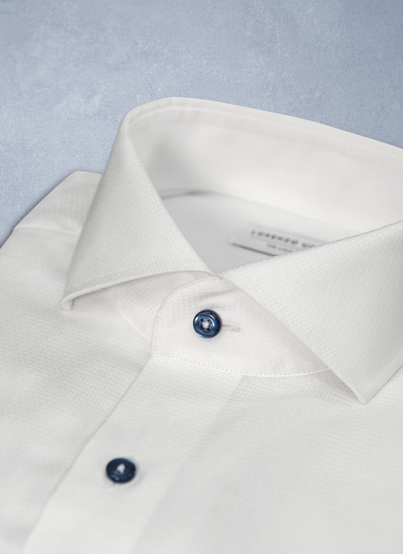 collar detail of white shirt with navy buttons 