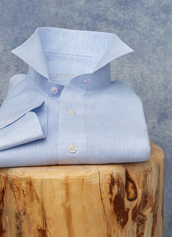 blue linen shirt sitting on a wood stool with pop collar