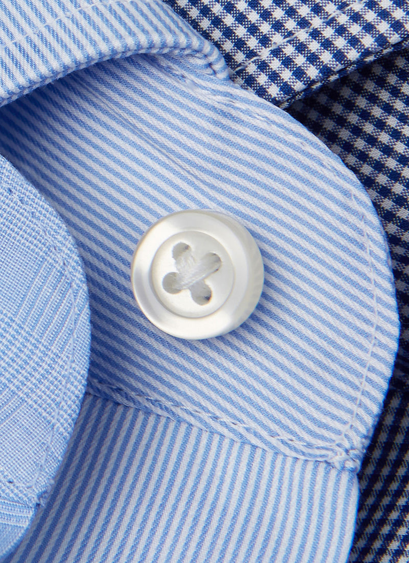 detail of blue thin stripe shirt with white button and button threads grouped with a navy gingham fabric and blue glen plaid fabric
