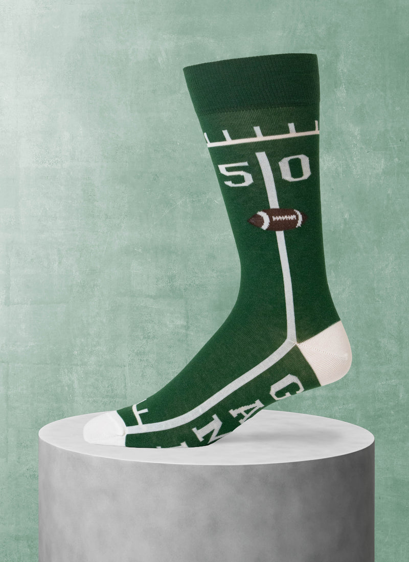 Green sock with football design on a gray pedestal against a green background
