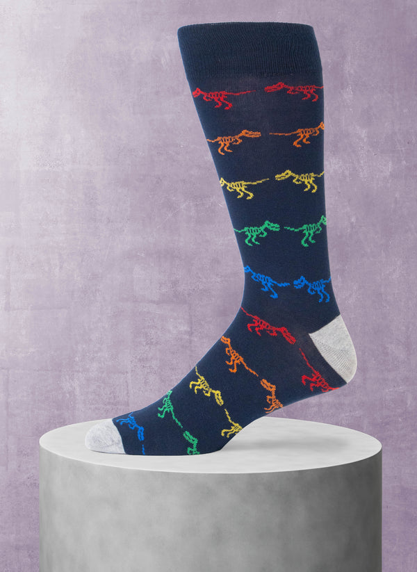 Navy sock with colorful dinosaur pattern on a gray pedestal against a purple background
