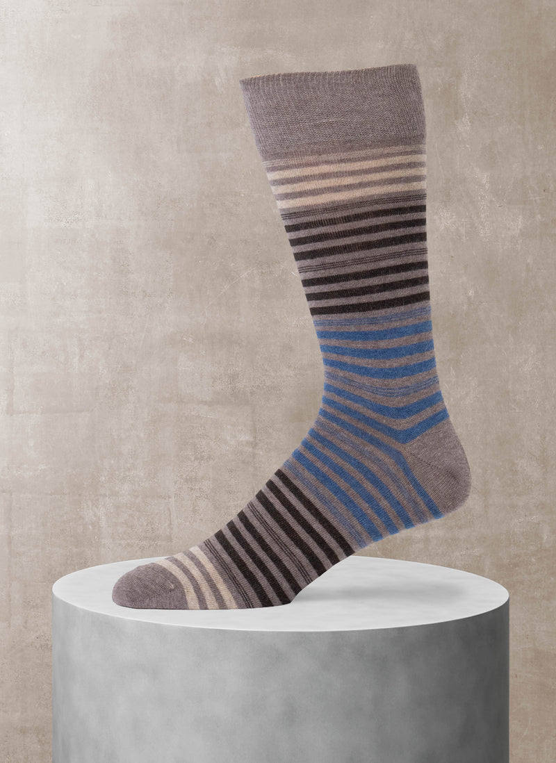 Striped sock on a cylindrical concrete block against a beige wall