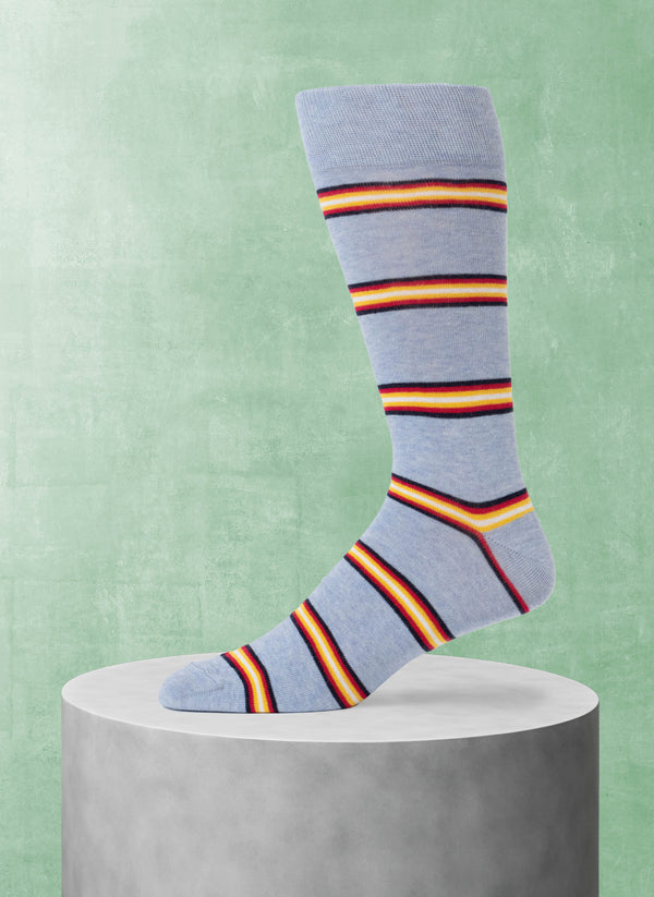 Light blue sock with multicolor stripes on a gray pedestal against a green background