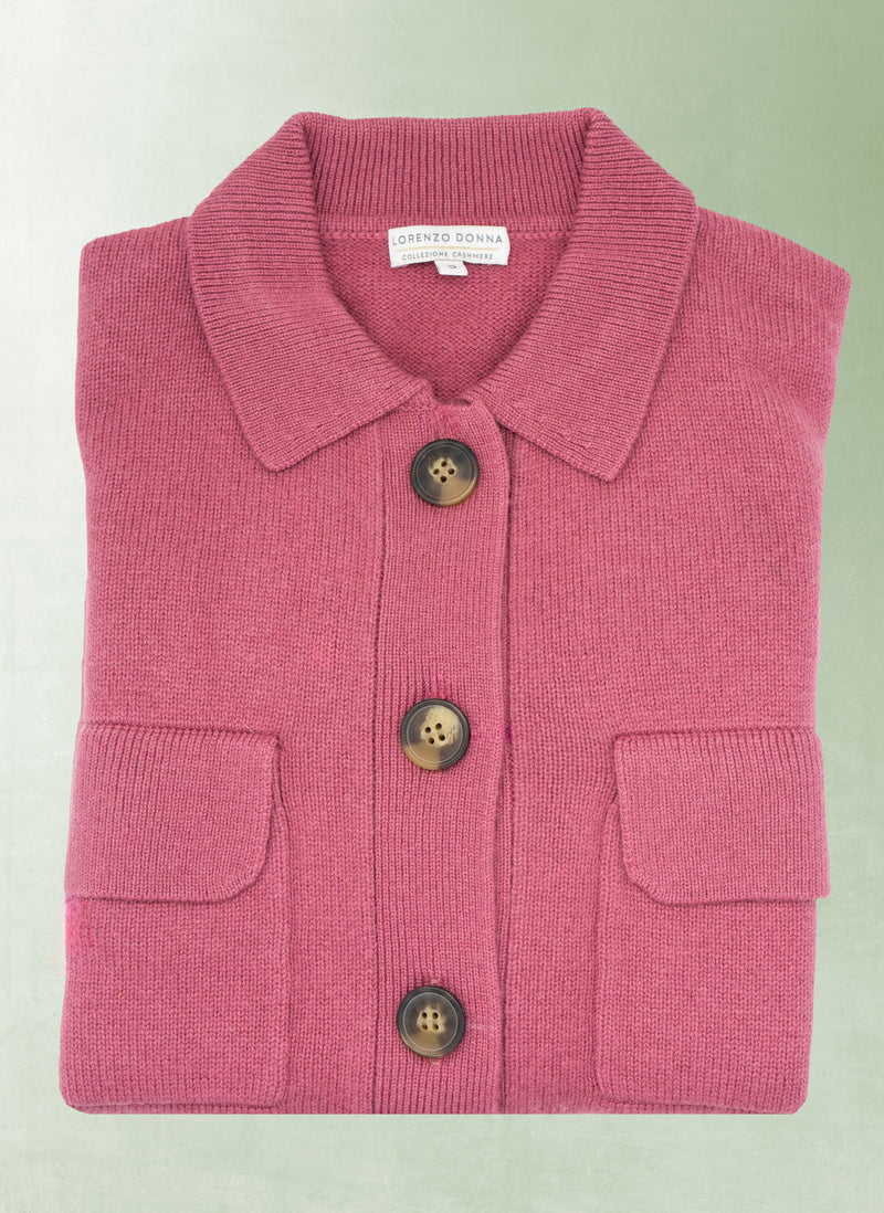 Folded pink cardigan with buttons on a light green background