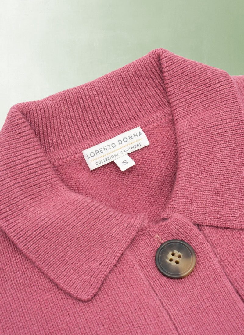 Close-up of a pink sweater with a button and Grenzo Donna label on a light green background