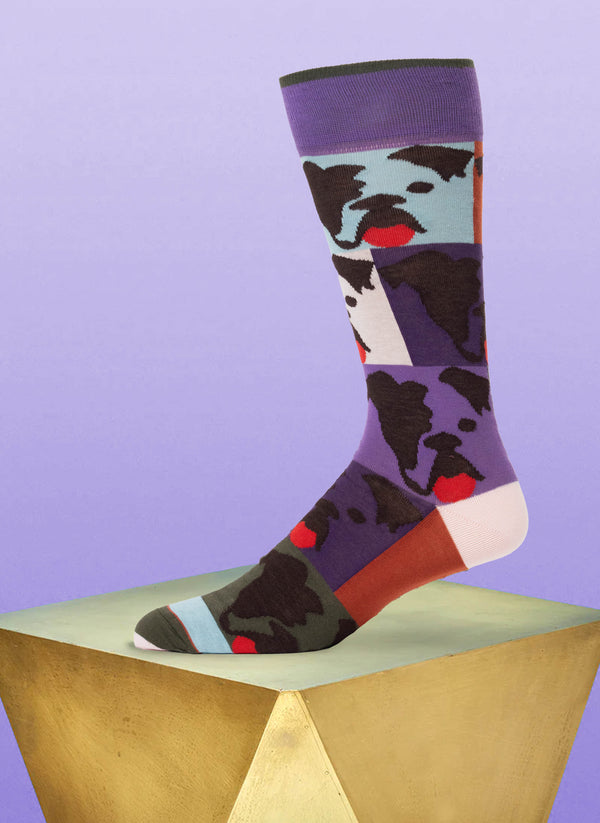 Colorful sock with dog pattern on a geometric wooden block against a purple background