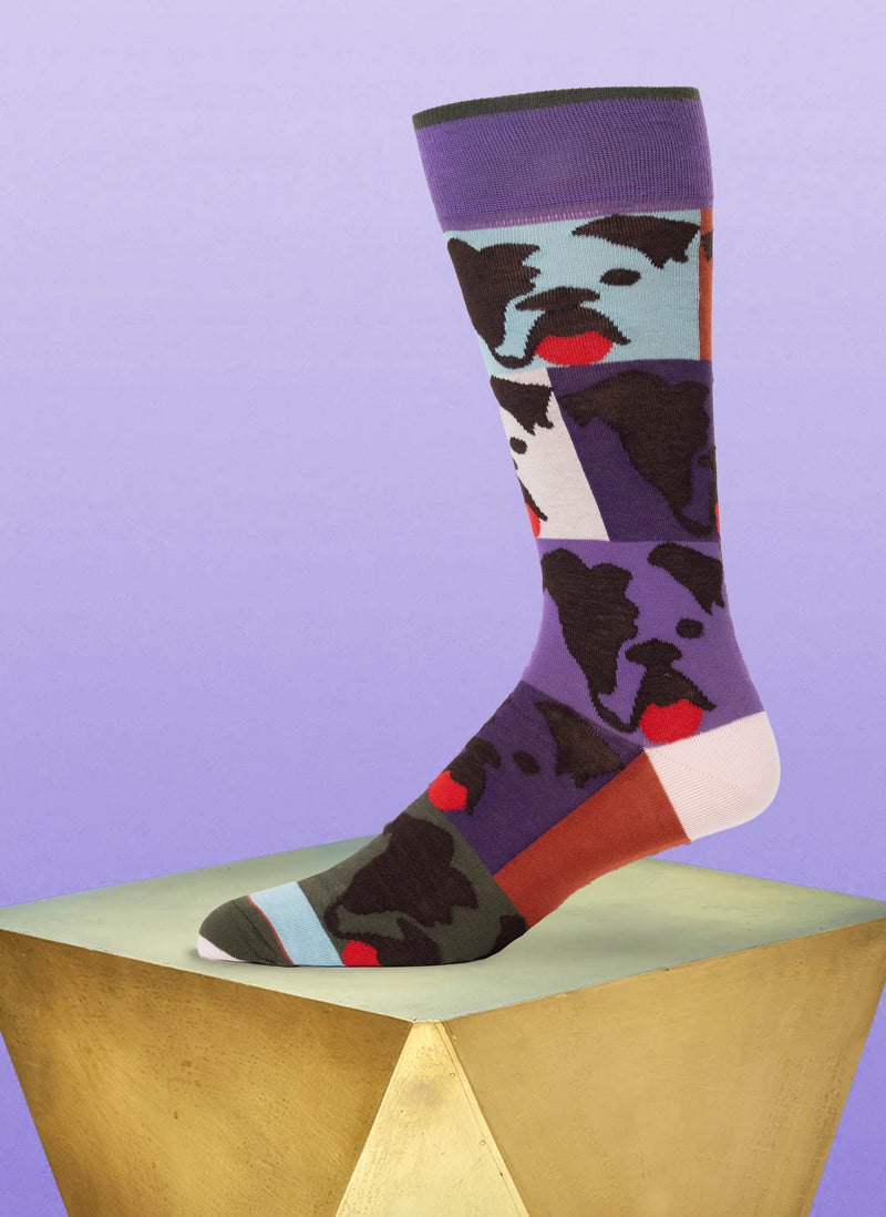 Colorful sock with dog pattern on a geometric wooden block against a purple background