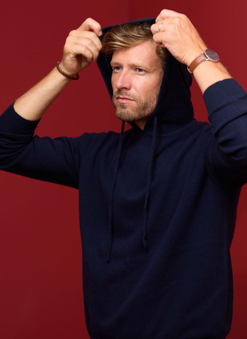 Man wearing a navy blue hoodie against a red background