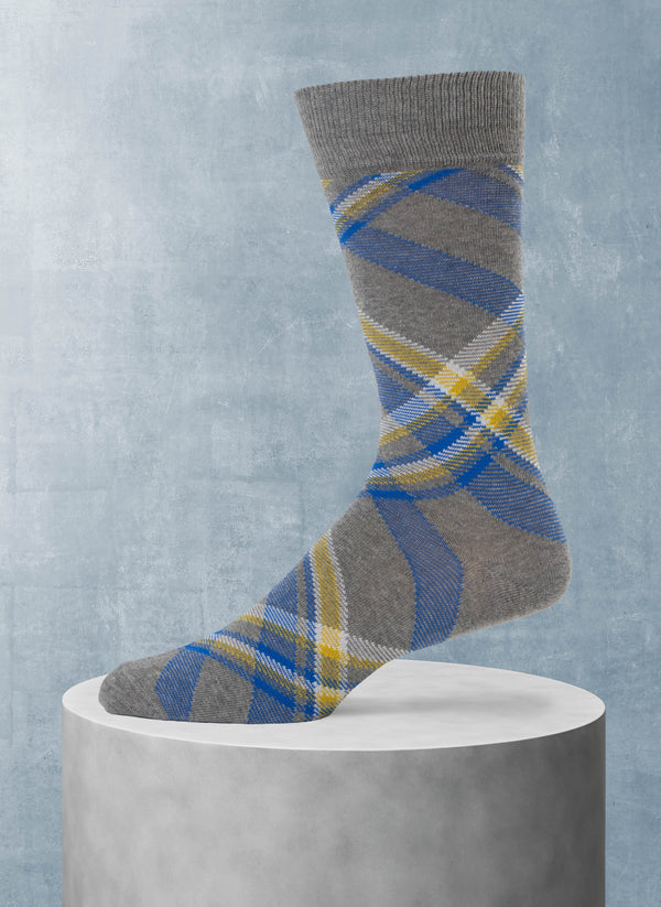 Plaid patterned sock on a gray pedestal against a light blue background