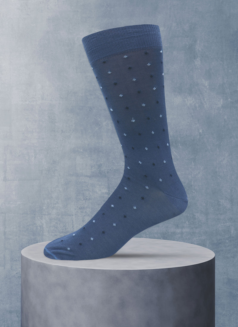 Blue sock with white polka dots on a gray pedestal against a gray background