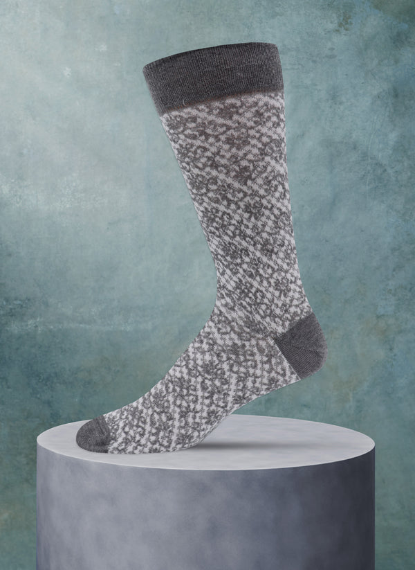 Patterned sock on a cylindrical gray stand against a textured blue background