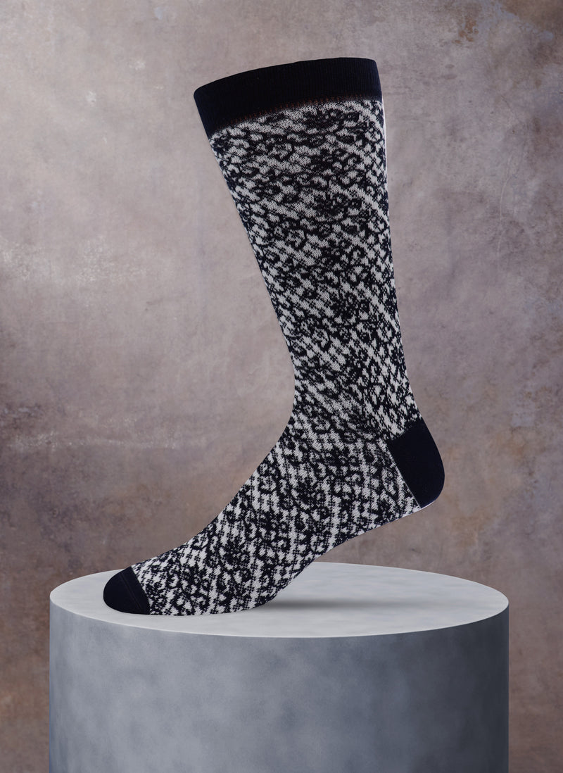 Black and white patterned sock on a gray pedestal against a beige background
