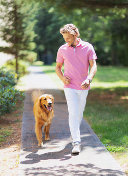Model walking with dog in Polo Shirt in Coral Heather