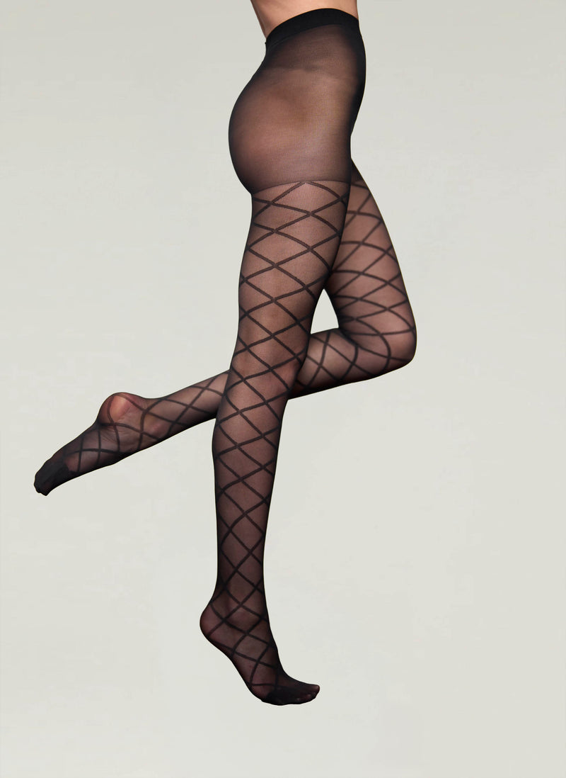 Black fishnet tights worn by a person on a plain background