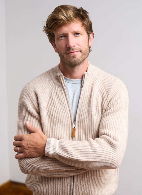 Man wearing a beige sweater with a neutral background