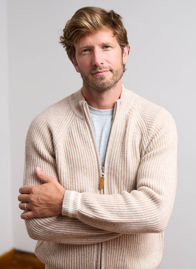 Man wearing a beige sweater with a neutral background