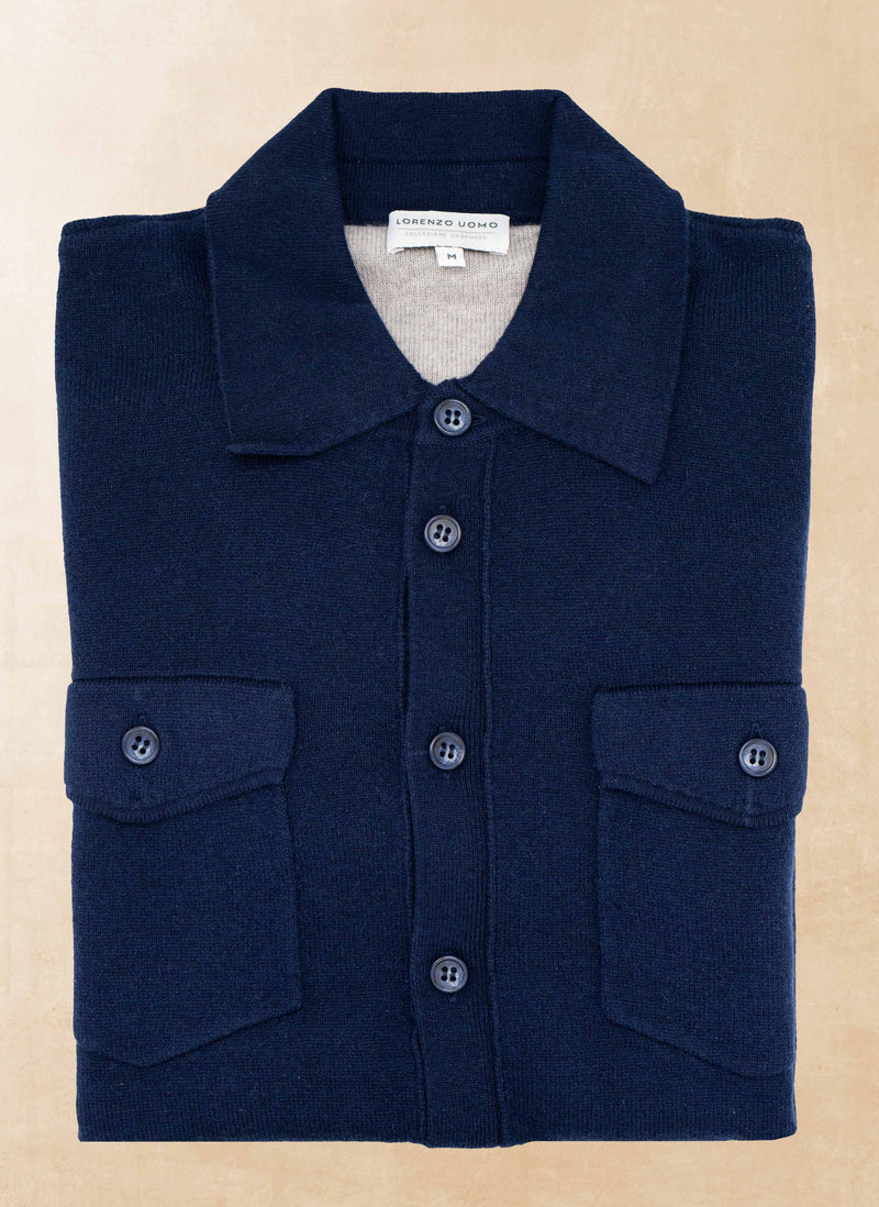 Folded navy blue shirt with button details on a beige background