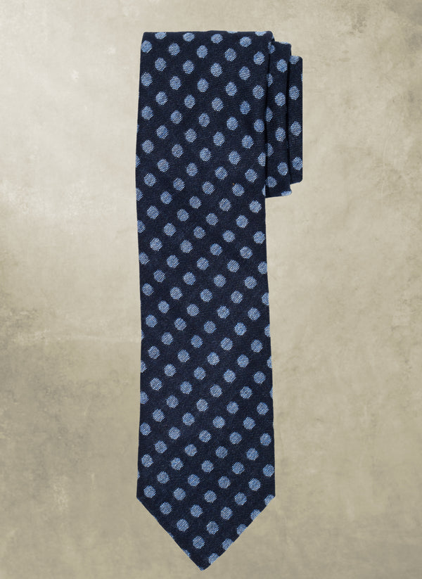 Navy blue tie with light blue polka dots on a beige background