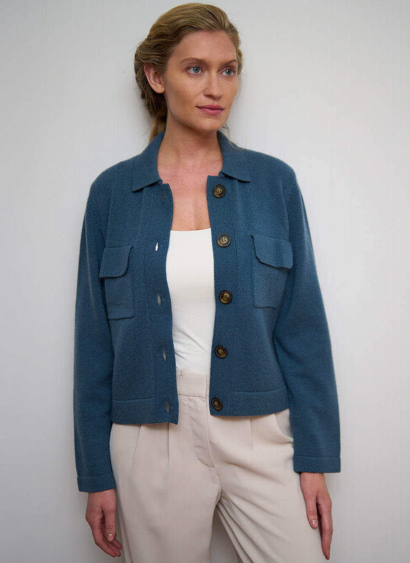 Woman wearing a blue jacket with button details on a plain background