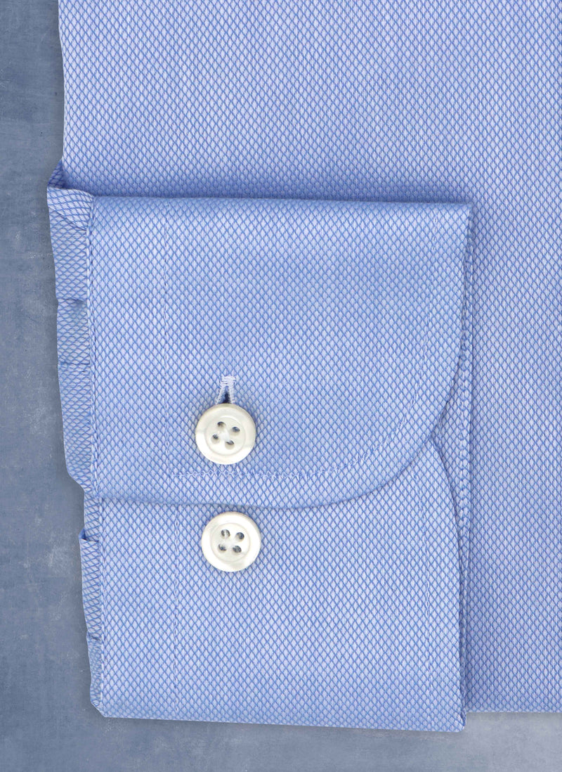 cuff detail of blue textured shirt with white buttons, button hole and button threads