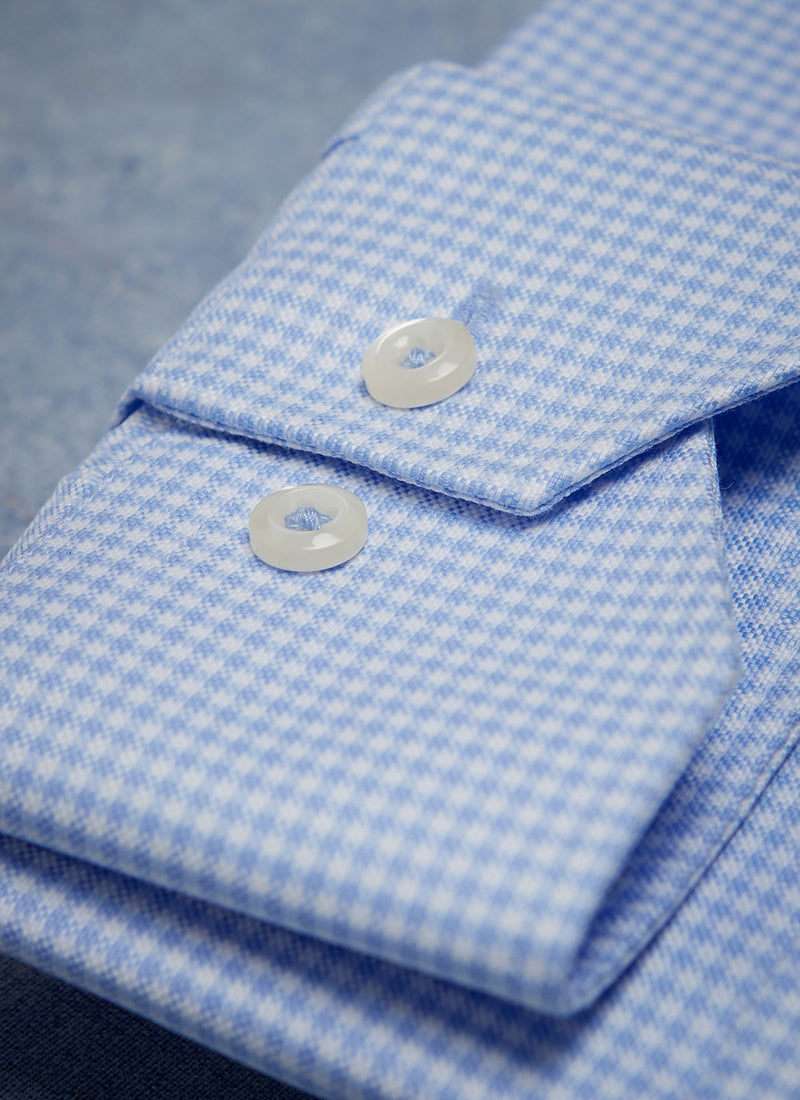 cuff detail of blue gingham shirt with white buttons and light blue button threads