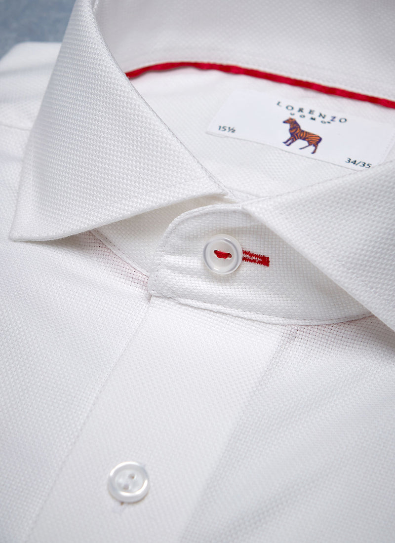 collar detail of white shirt with red button hole and thread as well as a red trim inside collar